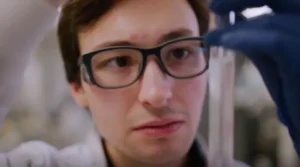 Man with glasses in lab holding pipette
